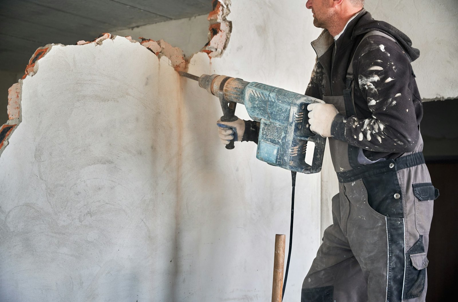 Cropped view worker with perforator during demolition wall.